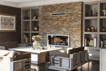 Encadré par deux grandes niches bibliothèque en chêne cérusé, le mur de la cheminée est ici habillé de barrettes d’ardoise oxydée de 10 cm d’épaisseur.