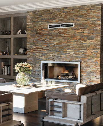 Encadré par deux grandes niches bibliothèque en chêne cérusé, le mur de la cheminée est ici habillé de barrettes d’ardoise oxydée de 10 cm d’épaisseur.