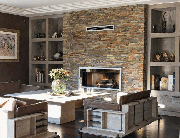 Encadré par deux grandes niches bibliothèque en chêne cérusé, le mur de la cheminée est ici habillé de barrettes d’ardoise oxydée de 10 cm d’épaisseur.