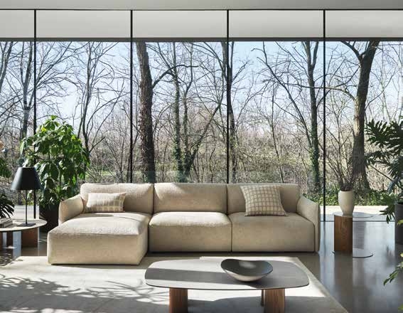 canapé d’angle beige dans un salon lumineux avec vue sur la nature et grandes fenêtres