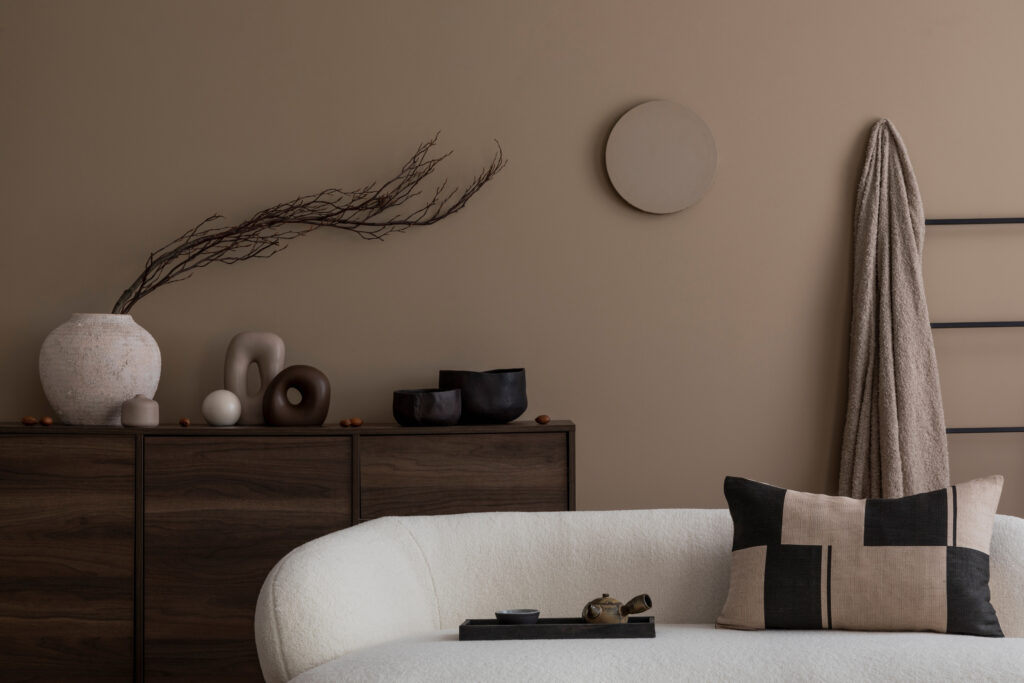 salon minimaliste aux tons beige avec canapé arrondi, mobilier en bois foncé et décoration naturelle