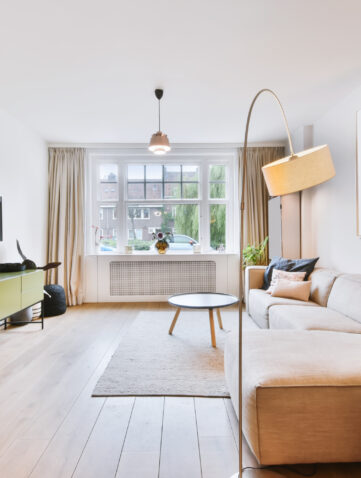 Petit salon lumineux aux tons clairs avec mobilier bas et miroir pour agrandir visuellement l’espace