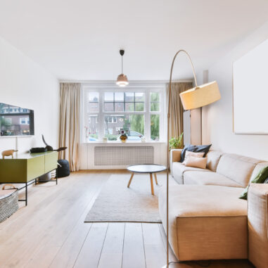 Petit salon lumineux aux tons clairs avec mobilier bas et miroir pour agrandir visuellement l’espace