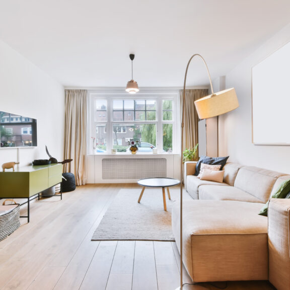 Petit salon lumineux aux tons clairs avec mobilier bas et miroir pour agrandir visuellement l’espace