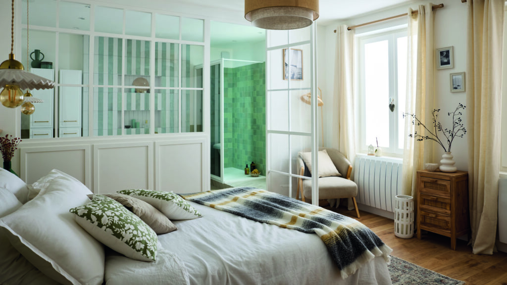 Suite parentale au style naturel, séparée d'une salle de bain en zellige vert par une élégante verrière blanche.
