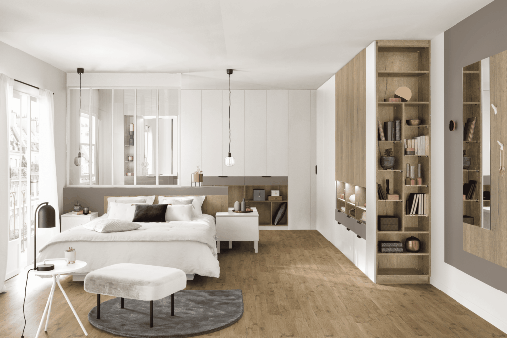 Chambre spacieuse et moderne associant bois clair et blanc, avec un grand dressing intégré et une verrière intérieure en tête de lit.