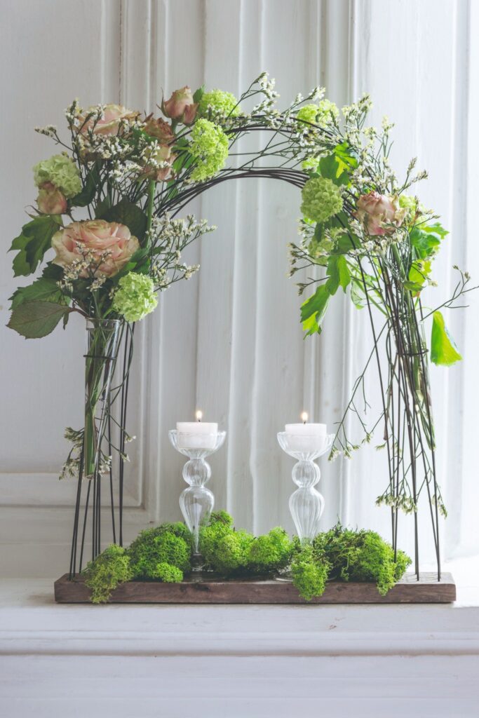 composition florale en arche avec bougies et fleurs fraîches décoration intérieure
