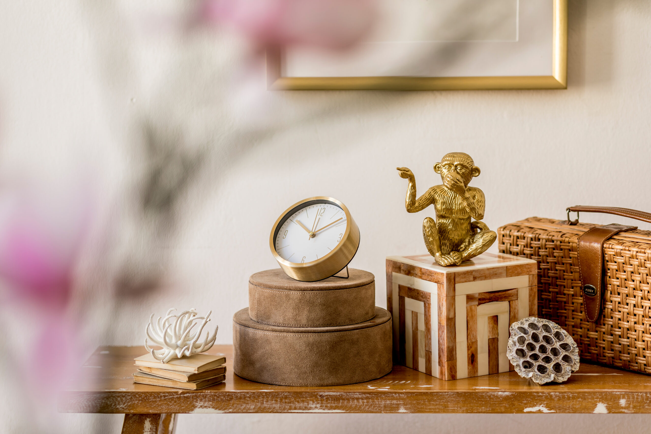 Objets décoratifs sur console en bois avec horloge, statue dorée et accessoires dans un intérieur élégant