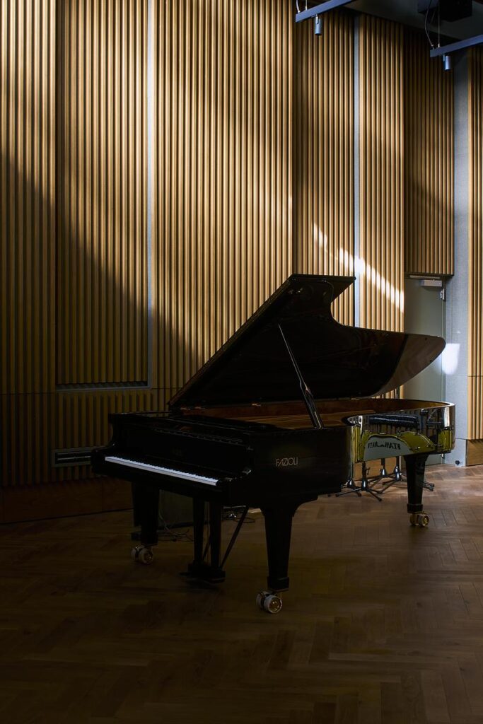 Piano à queue dans un studio d’enregistrement avec murs acoustiques en bois et lumière naturelle