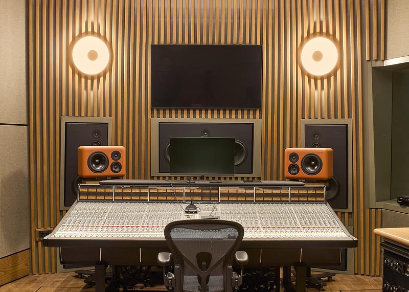 Studio d’enregistrement professionnel avec console de mixage et enceintes dans un espace acoustique design en bois