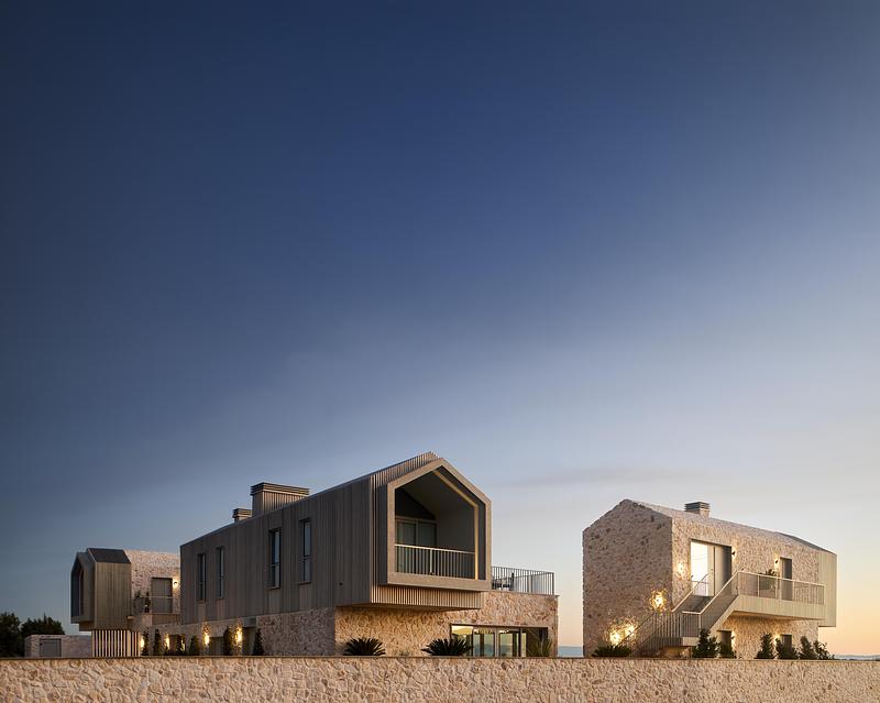 Architecture contemporaine en pierre et bois sur la côte égéenne avec bâtiments modernes intégrés dans le paysage