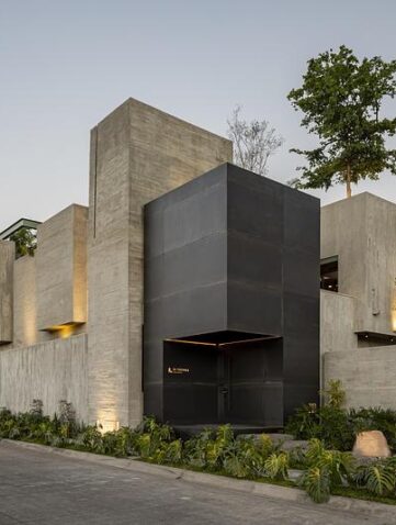 Façade en béton brut d’un studio d’architecture au Mexique avec arbre en arrière-plan et volumes minimalistes