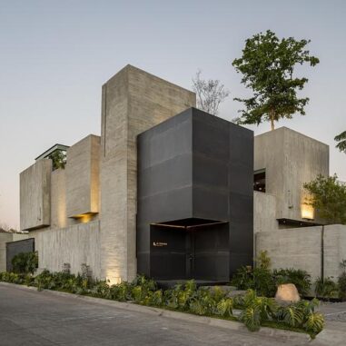 Façade en béton brut d’un studio d’architecture au Mexique avec arbre en arrière-plan et volumes minimalistes