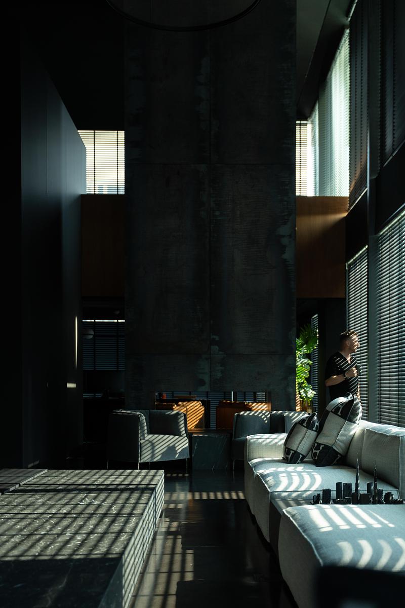 Intérieur minimaliste avec murs texturés, mobilier contemporain et lumière naturelle filtrée dessinant des ombres graphiques