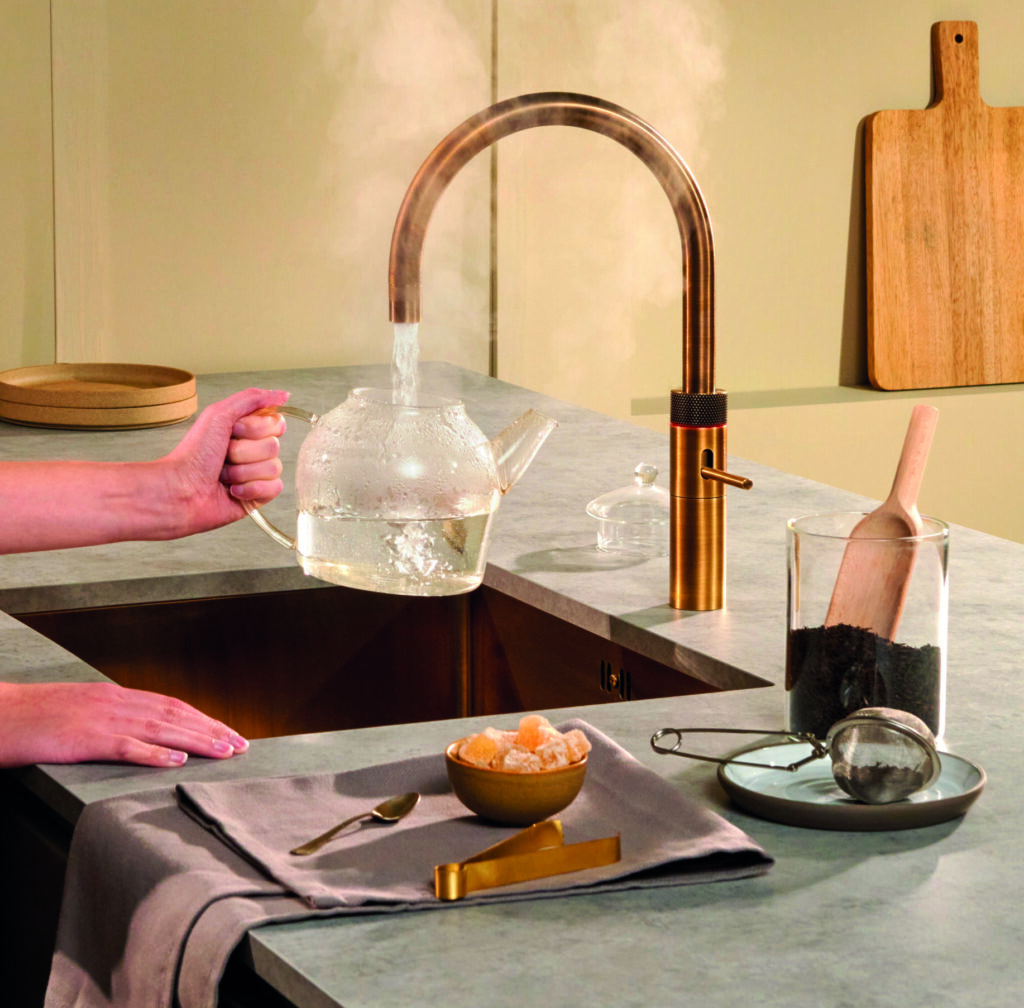 Robinet Quooker en laiton patiné préparant une théière avec eau bouillante instantanée