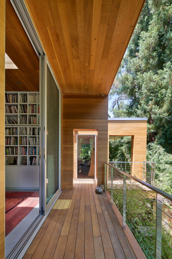 Couloir en bois avec bibliothèque intégrée et vue sur les arbres