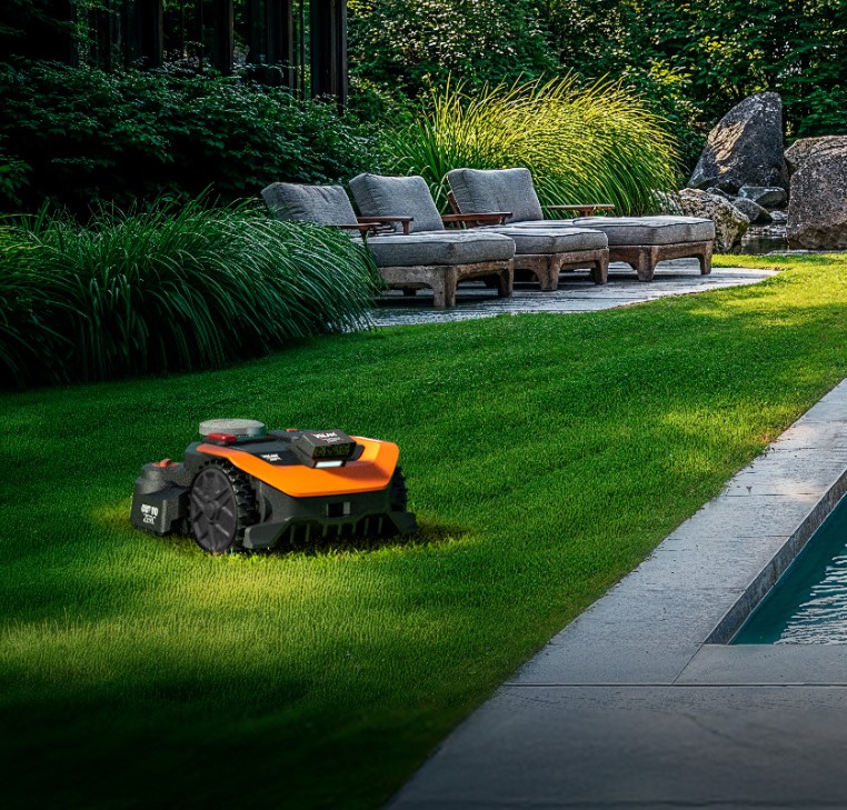 Robot tondeuse WORX Vision Cloud en fonctionnement dans un jardin contemporain avec piscine et aménagement paysager luxuriant.
