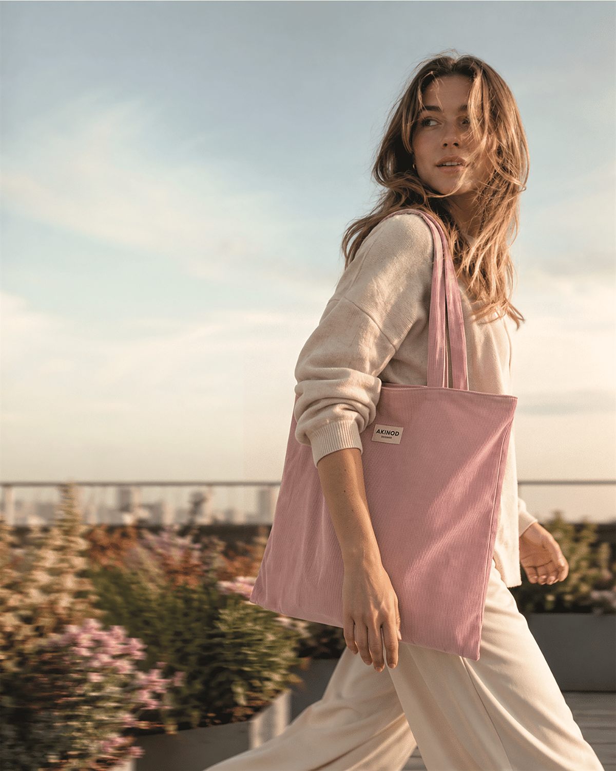 Tote bag rose Akinod porté sur un rooftop urbain