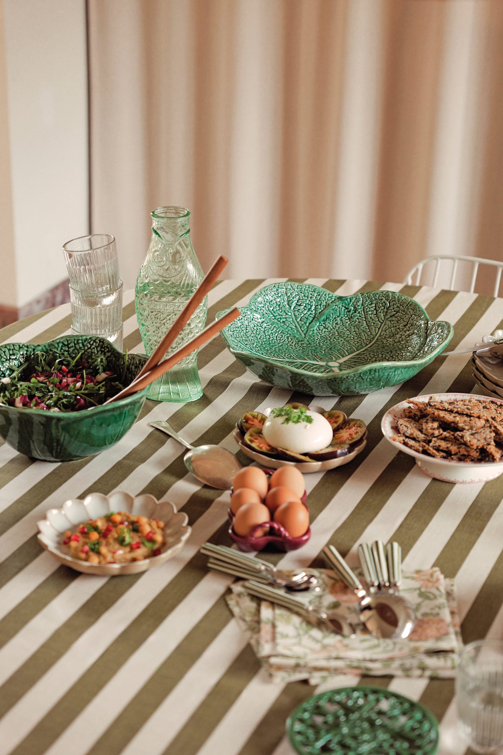 Dressage de table en extérieur avec assiettes creuses blanches à motifs feuilles, sets de table en jute et bougies