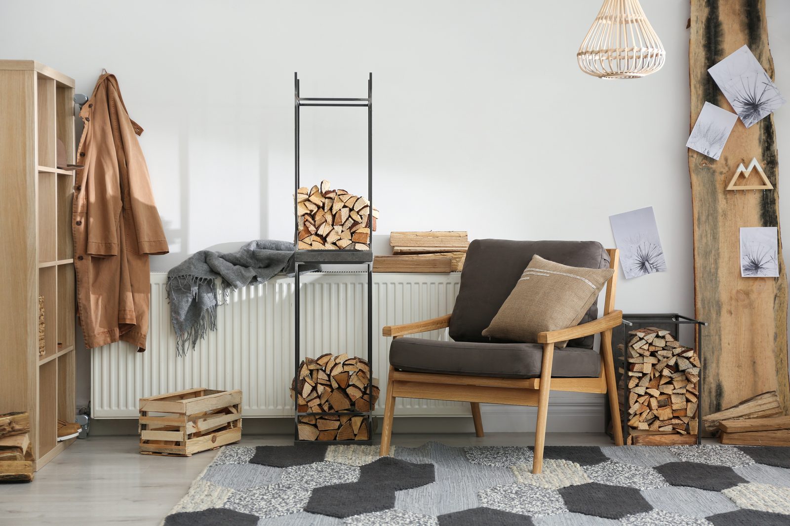 Coin d’entrée avec deux racks en métal garnis de bûches, un fauteuil en bois et un tapis à motifs hexagonaux gris et noirs