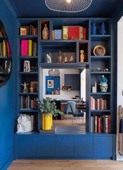 Bibliothèque bleue sur mesure encadrant une niche ouverte qui forme un coin lecture