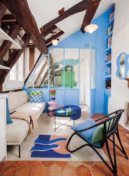 Séjour sous charpente avec murs bleus et verrière séparant une pièce en enfilade, tomettes au sol