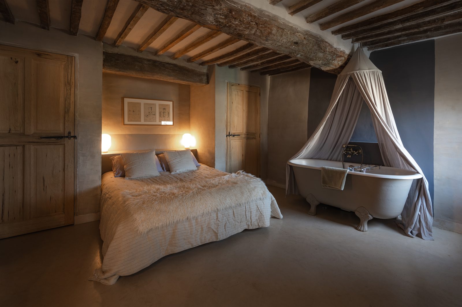 Chambre de bergerie rénovée avec baignoire sur pieds sous les poutres