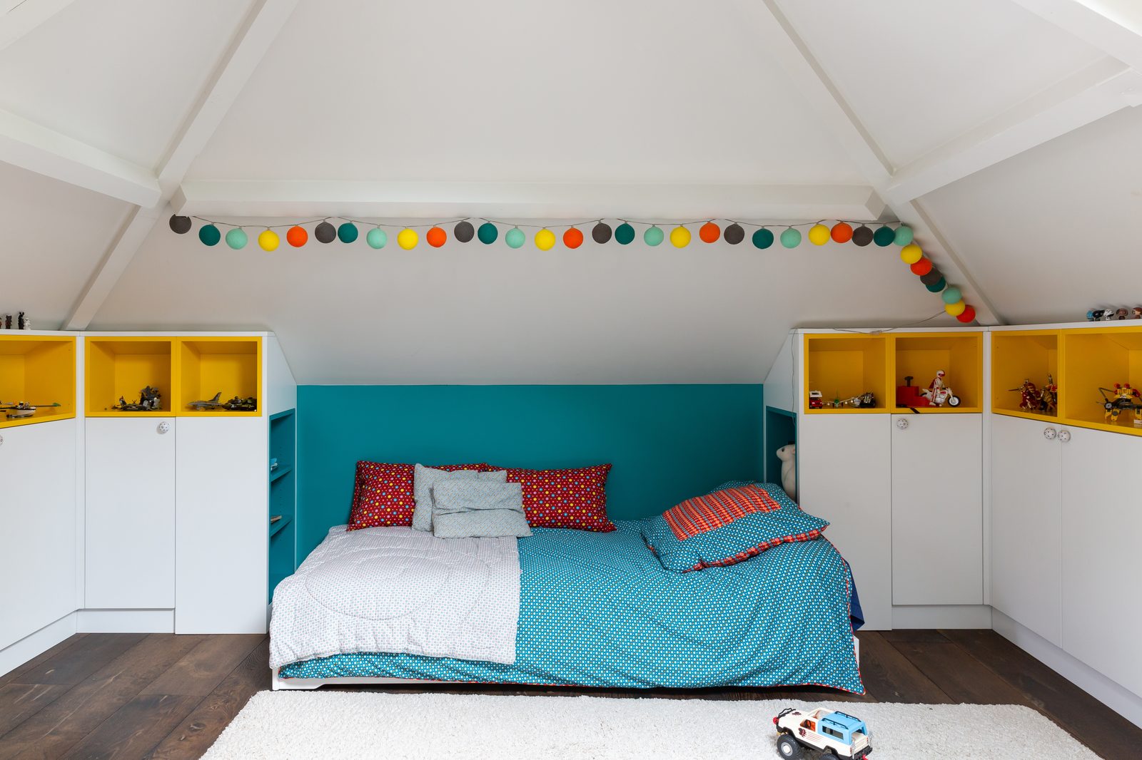 Chambre d'enfant sous combles avec rangements intégrés et guirlande colorée