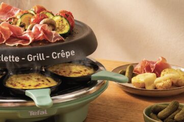 Appareil à raclette Tefal Raclette Célébration vert sauge, poêlons de fromage fondu sous une plaque garnie de jambon cru et de légumes grillés